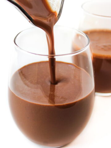 Healthy vegan chocolate milkshake being poured into glasses