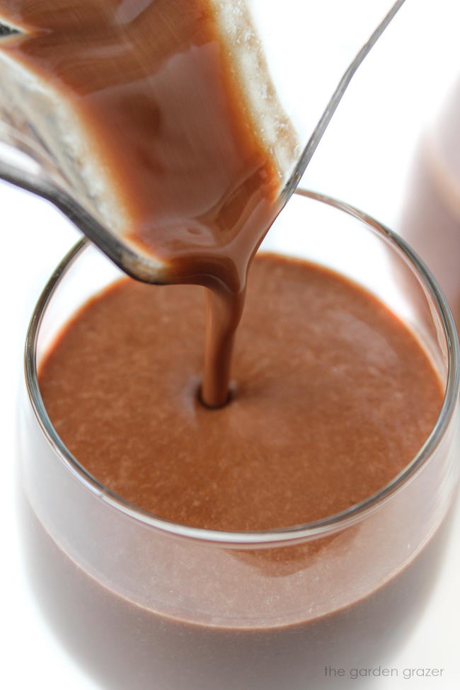 Pouring healthy chocolate milkshake into a glass