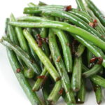 Asian-style garlic green beans on a white plate