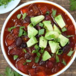 Small white bowl with bean chili on a wooden table