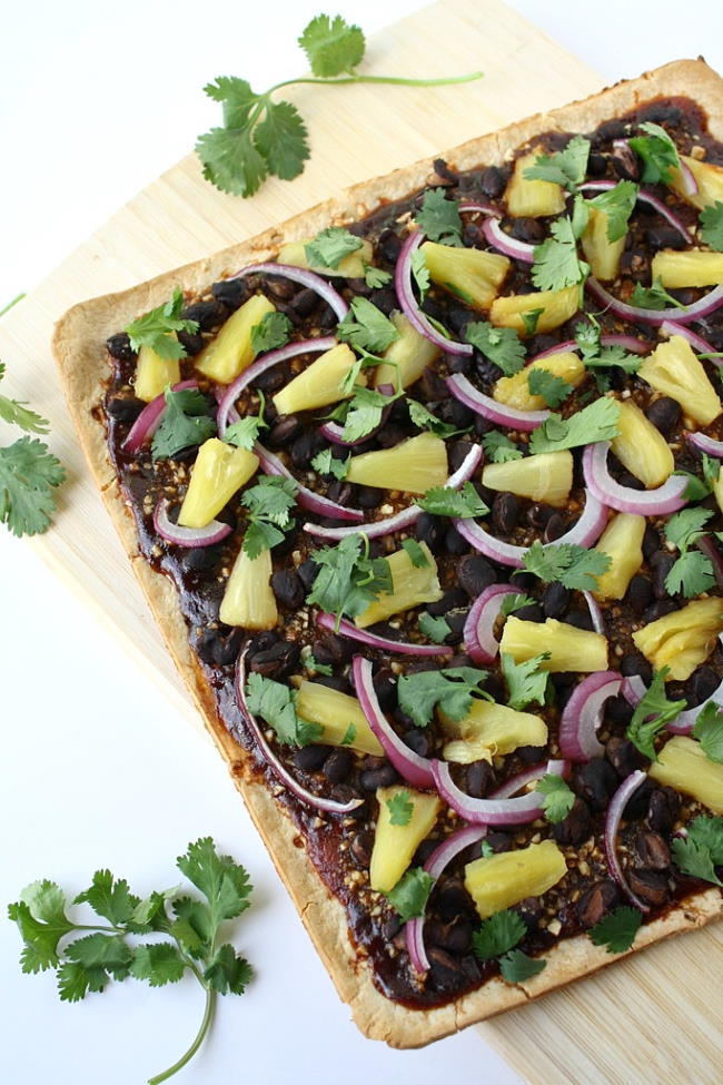 Vegan BBQ pizza with pineapple and black beans cut on a cutting board