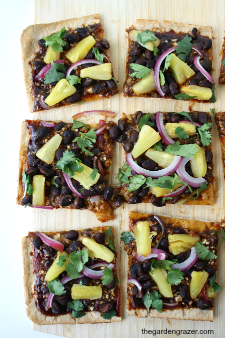 Vegan BBQ pizza with pineapple and black beans cut on a cutting board