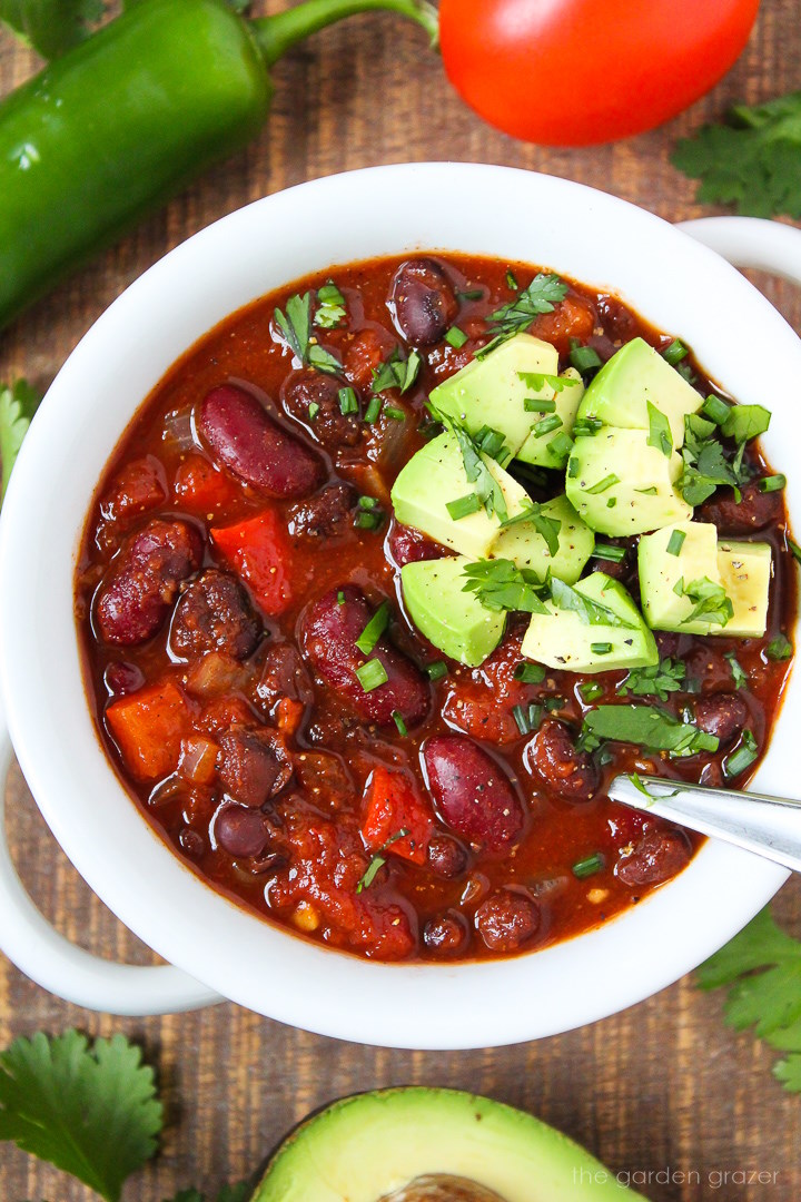 Close-up view of hearty vegan chili in a white bowl on a wooden table