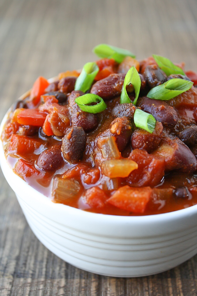 Hearty vegan black bean chili in a bowl with green onions sprinkled on top