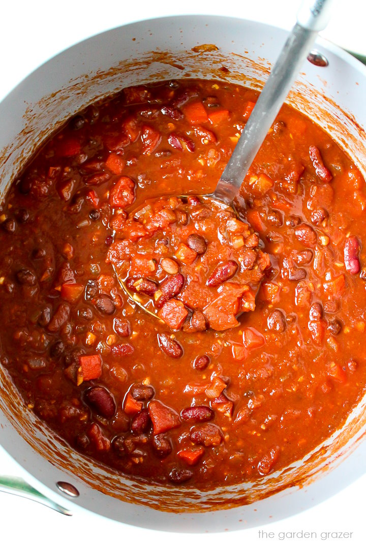 Overhead view of hearty vegan chili cooking in a large pot with ladle