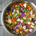 Vegan vegetable soup in a pot with large stirring spoon