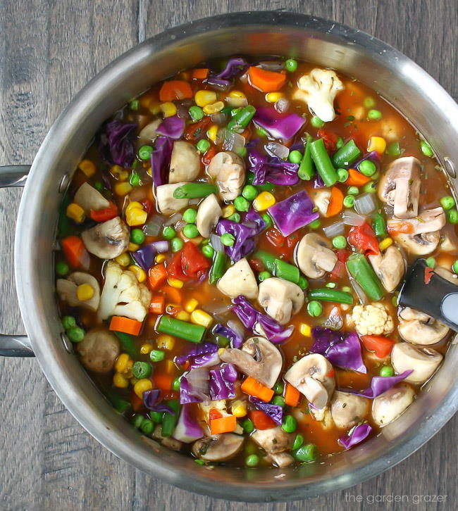 Pot of cooked vegetable soup with serving spoon