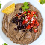 Creamy black bean avocado dip served in a white bowl with tortilla chips