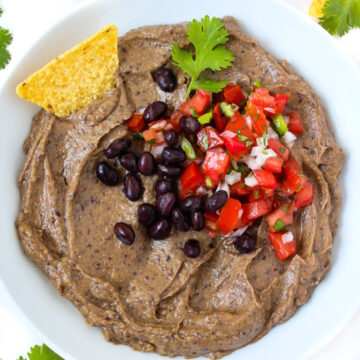 Creamy black bean avocado dip served in a white bowl with tortilla chips