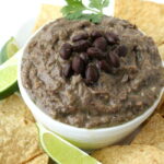 Vegan black bean avocado dip in a bowl with chips on the side