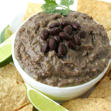 Vegan black bean avocado dip in a bowl with chips on the side