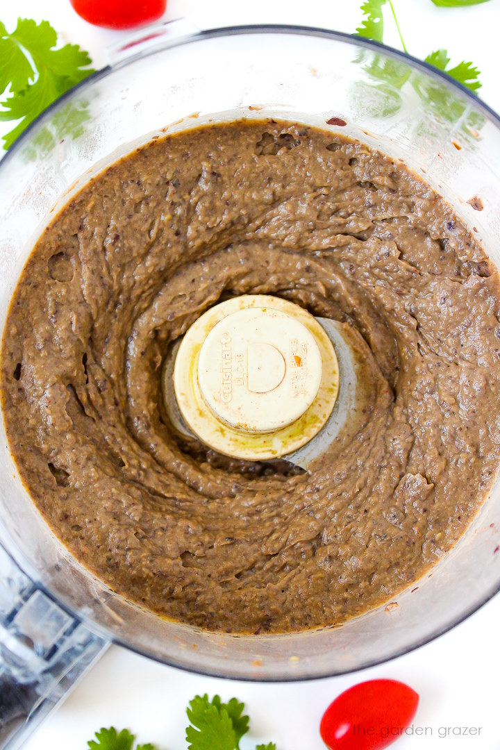 Overhead view of creamy black bean avocado dip in a food processor after blending