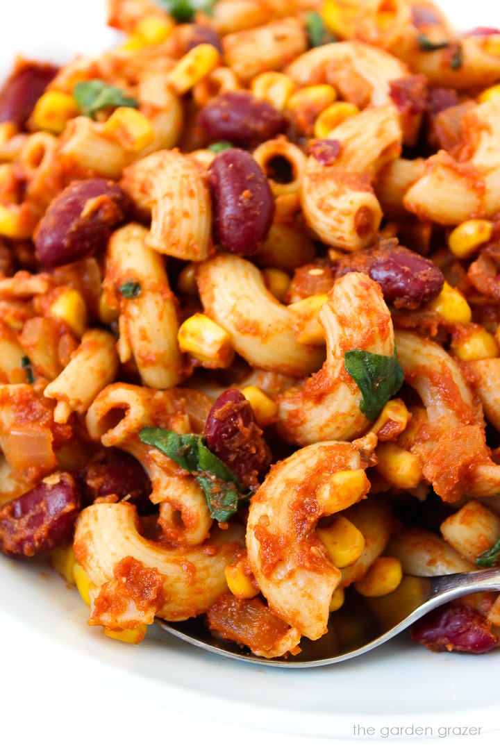 Close up view of vegan chili mac served on a white plate with fork