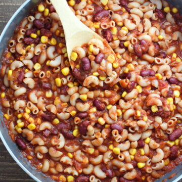 Vegan chili mac in a large skillet with wooden spoon