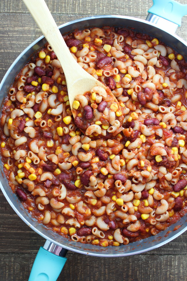 Vegan chili mac in a large skillet with wooden spoon