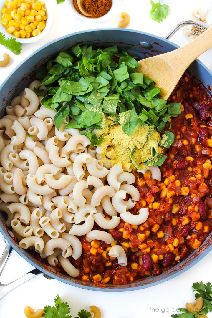 Overhead view of preparing chili mac ingredients in a large skillet before mixing together