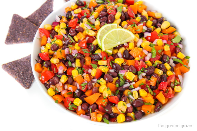 Beans, sweet corn, tomatoes and onion in a white bowl with garlic dressing