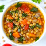 Close up view of lentil spinach soup in a small white bowl