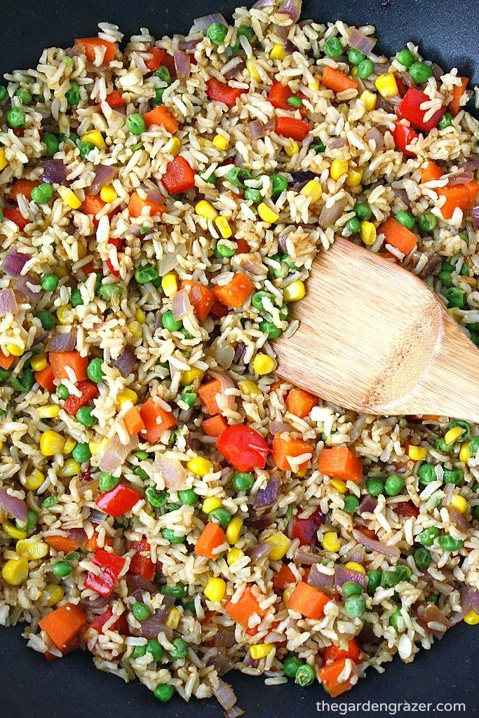 Skillet with vegetable fried rice with wooden spoon