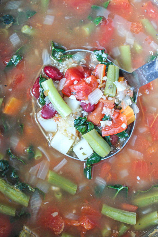 Quinoa minestrone cooking in a large stockpot with soup ladle