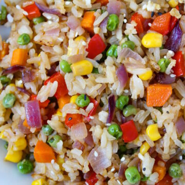 Close up view of rainbow veggie fried rice on a white plate