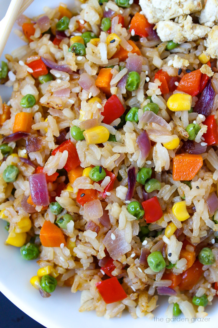 Close up view of rainbow veggie fried rice on a white plate