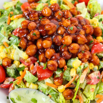 Close-up view of vegan BBQ chickpea salad with avocado ranch dressing on a white plate