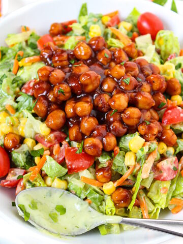 Close-up view of vegan BBQ chickpea salad with avocado ranch dressing on a white plate