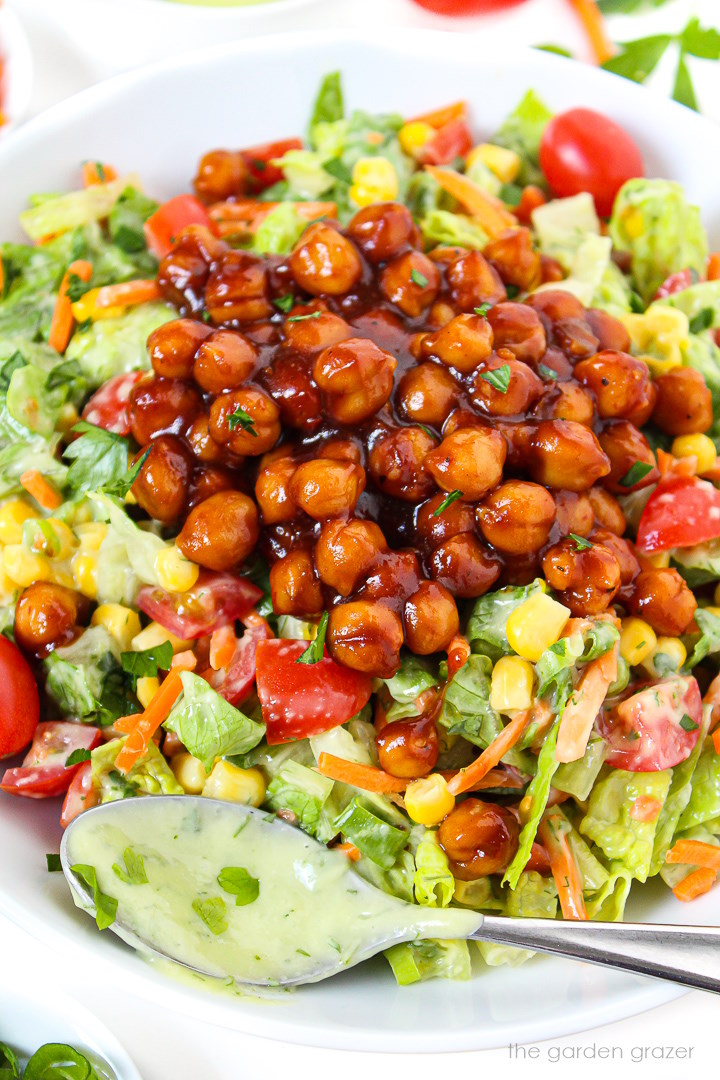 Close-up view of vegan BBQ chickpea salad with avocado ranch dressing on a white plate