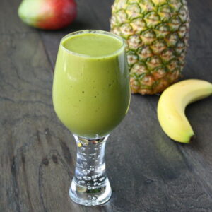 Glass of vegan tropical matcha smoothie with mango and pineapple