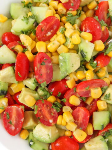 Avocado corn salad with cucumber and tomato in a white bowl
