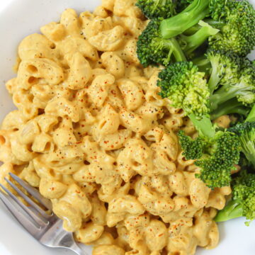 Vegan cashew mac and cheese in a white bowl with broccoli