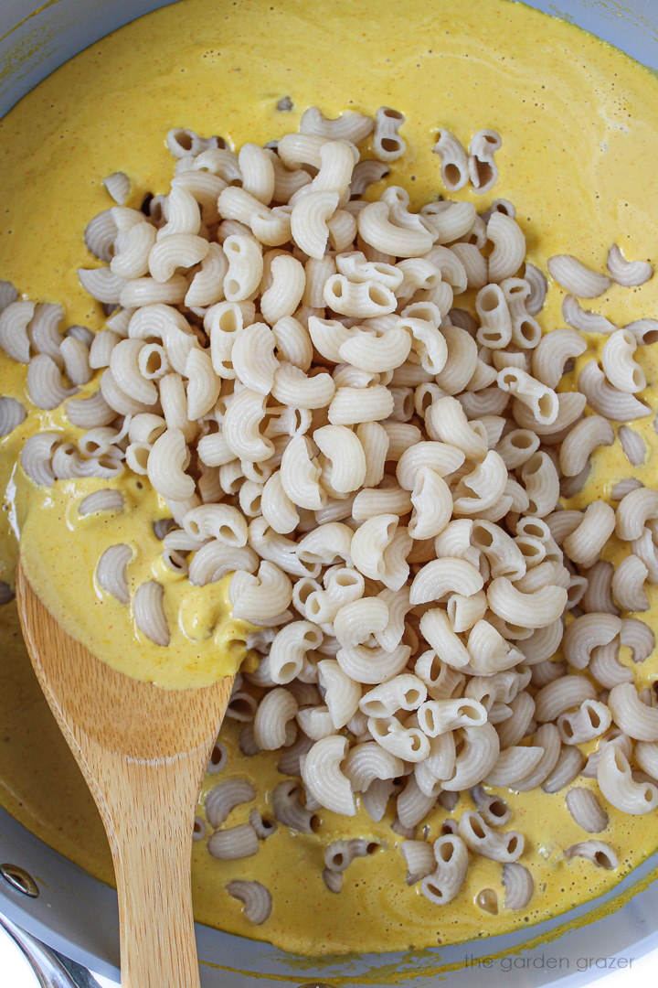 Preparing pasta with cashew sauce in a large skillet