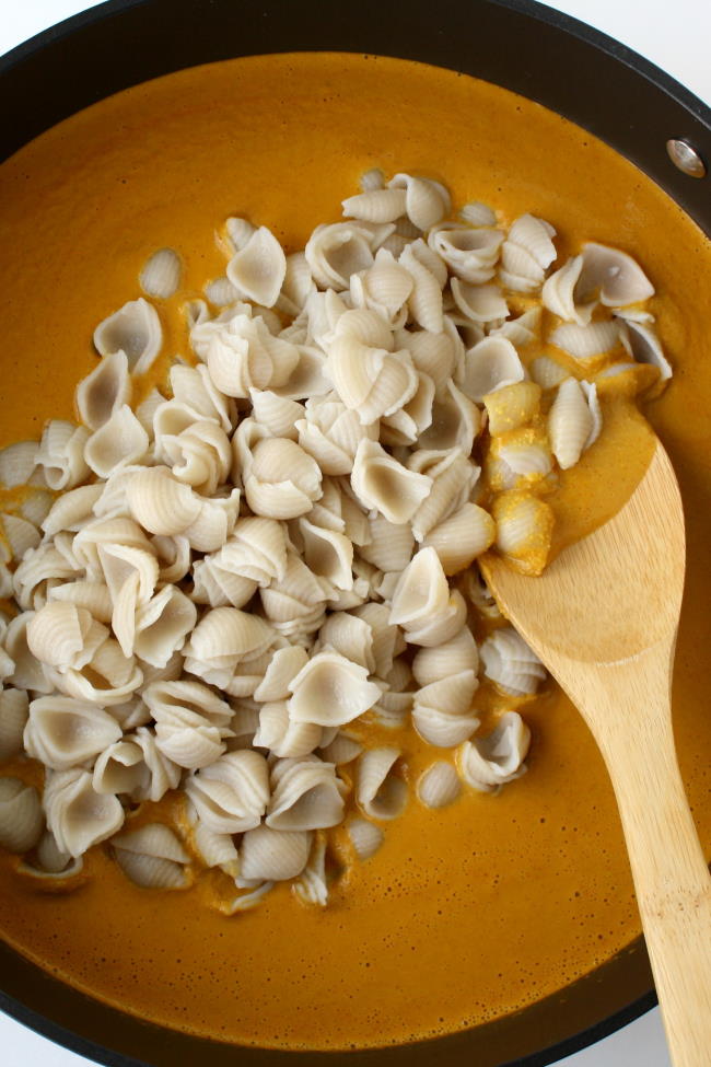 Preparing pasta with cashew sauce in a skillet