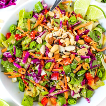 Overhead view of Asian Chopped Salad with sesame dressing in a white bowl with lime slices