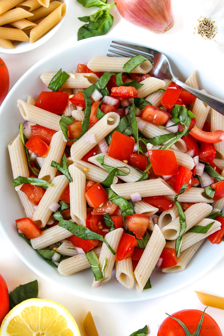 Fresh tomato basil pasta in a white serving bowl with fork