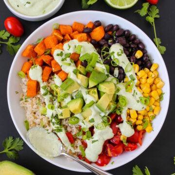 Overhead view of Mexican sweet potato black bean and rice bowl topped with a creamy cashew cilantro-lime sauce