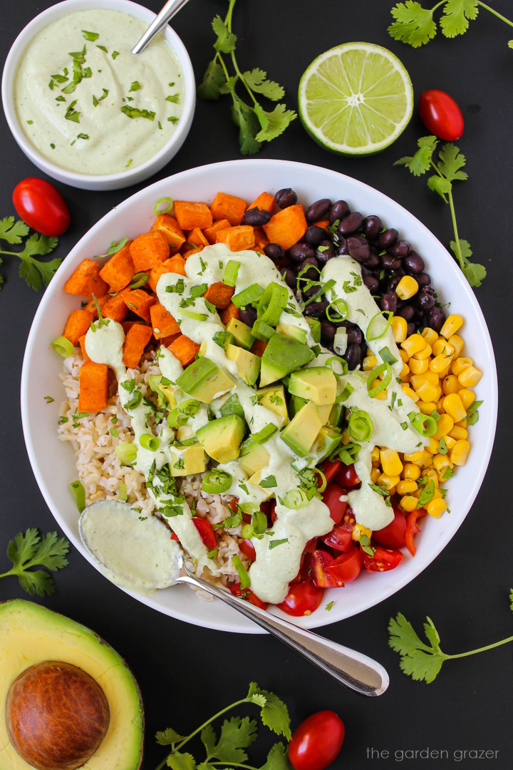 Overhead view of Mexican sweet potato black bean and rice bowl topped with a creamy cashew cilantro-lime sauce