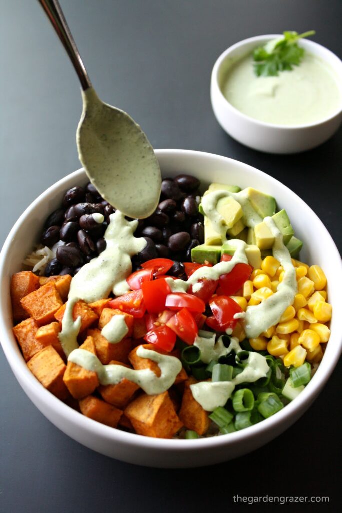 Vegan Mexican sweet potato bowl with dressing being spooned on top
