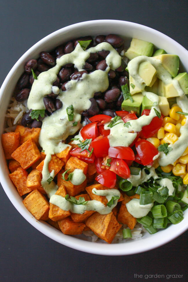 Vegan sweet potato bowl with black beans and cashew cream in a white bowl