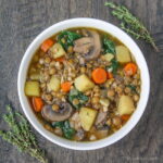 Bowl of vegan lentil potato soup garnished with thyme
