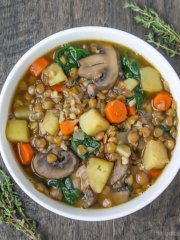 Bowl of vegan lentil potato soup garnished with thyme
