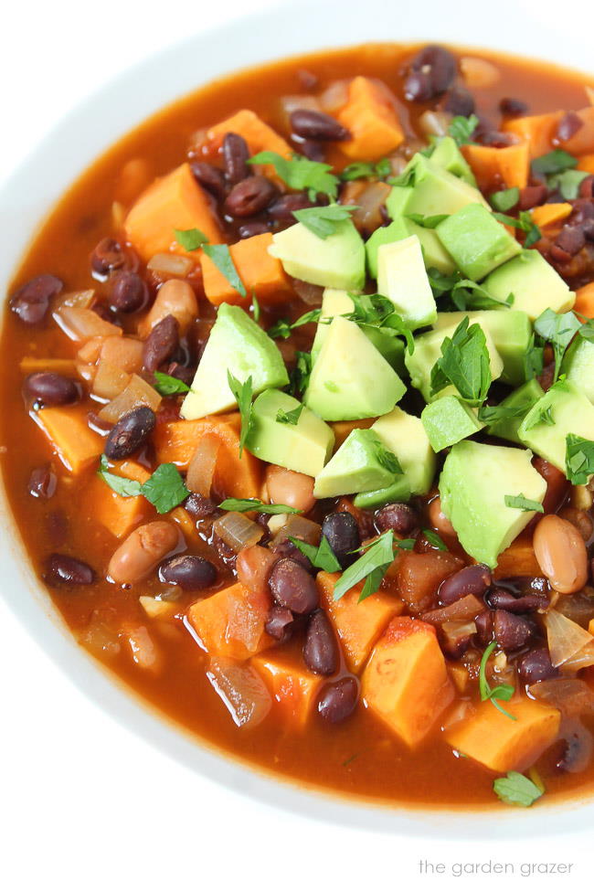 Bowl of sweet potato chili topped with avocado and cilantro