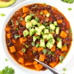 Overhead view of sweet potato black bean chili in a white bowl with spoon