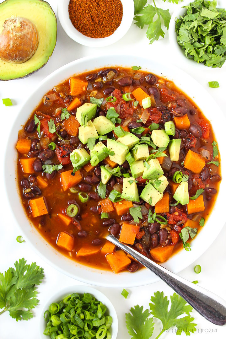 Overhead view of sweet potato black bean chili in a white bowl with spoon