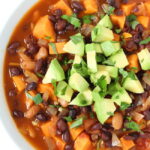 Bowl of vegan sweet potato black bean chili topped with avocado