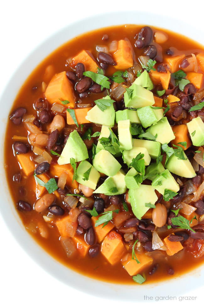 Bowl of vegan sweet potato black bean chili topped with avocado