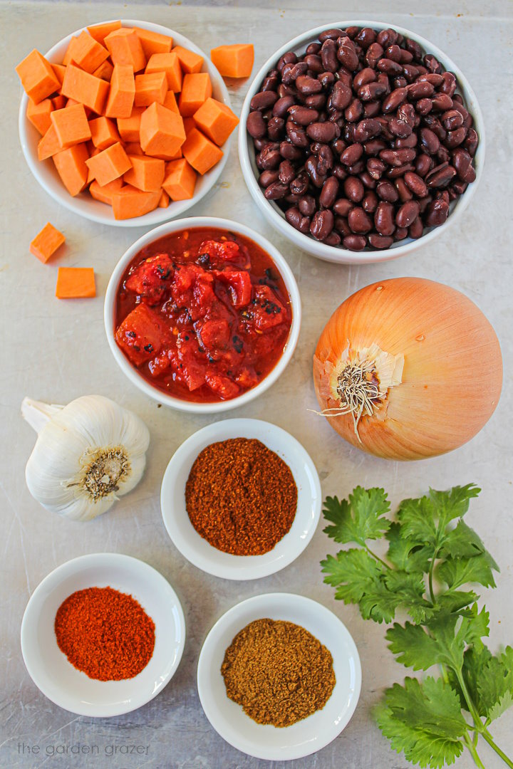 Beans, potato, tomato, onion, garlic, and spice ingredients laid out on a metal tray