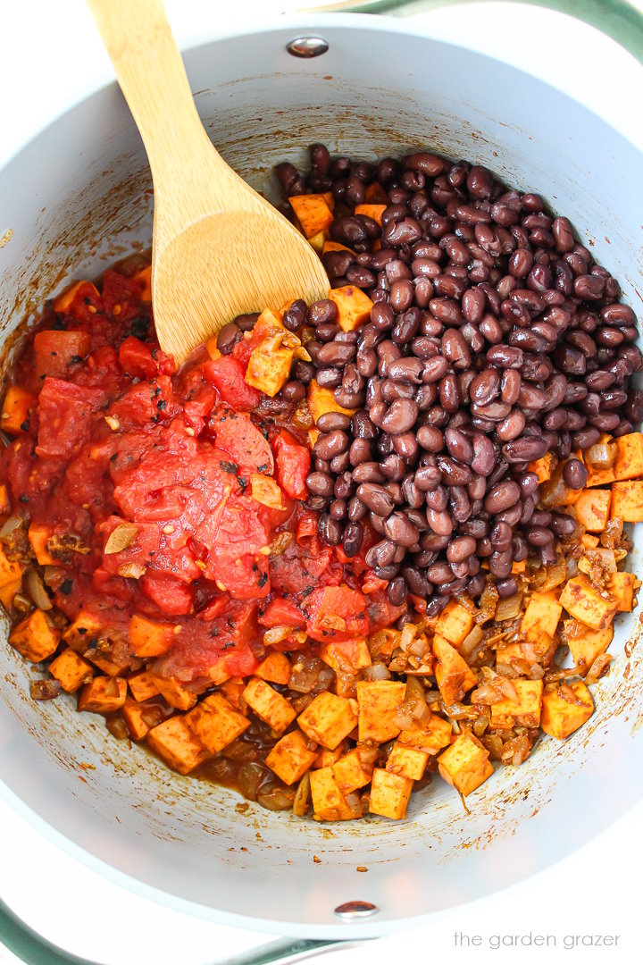 Overhead view of adding ingredients to a large pot for chili