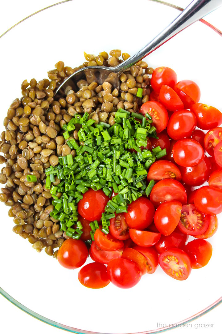 Overhead view of salad ingredients in a glass bowl before stirring together